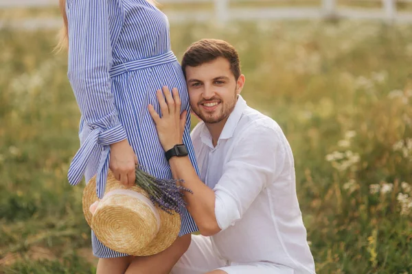 Ein Mann, der Schwangeren in der Natur zuhört. Mann im weißen Hemd und Frau im blauen Kleid — Stockfoto