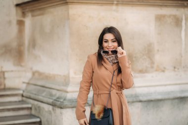 Sonbahar ceket ve güneş gözlüğü gülümseme kamera için çekici Bayan