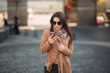 Çekici kız kullanım telefonu, şehir merkezinde. Sonbahar hava