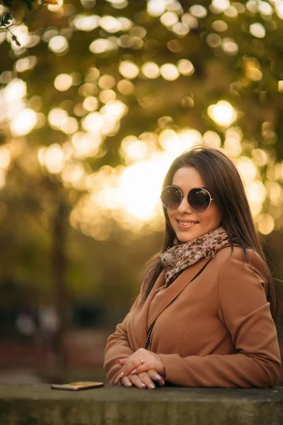 Snygg tjej i en brun kappa och en halsduk med glasögon. Makeup — Stockfoto