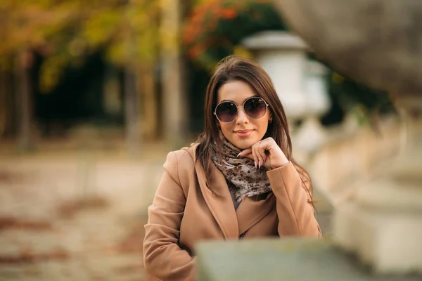 Şık kız kahverengi bir ceket ve gözlüklü bir eşarp. Makyaj — Stok fotoğraf
