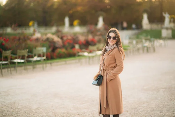 Stylisches Mädchen im Mantel posiert für Fotografen. Park — Stockfoto