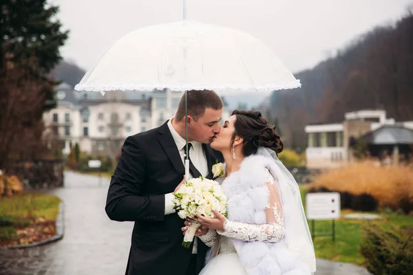 Ženich a nevěsta chůzi v parku na jejich svatební den. Podzimní počasí. Rair. Pár deštník — Stock fotografie