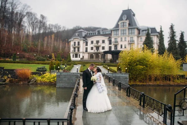 Casal feliz andando no dia do casamento na ponte. Grande parque com grande castelo. Tempo de outono e fundo colorido — Fotografia de Stock