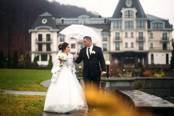 Um casal feliz a passear no dia do casamento. Grande parque com grande castelo. Tempo de outono e fundo colorido — Fotografia de Stock
