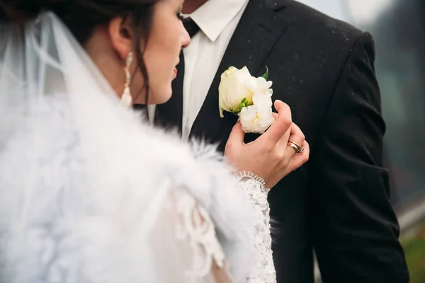 Groom and bride near the mirror building in in bad weather. They use umbrella