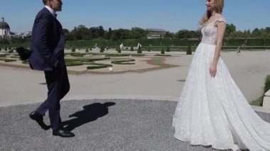 Çift büyük palace yanında yürümek. Zarif damat ve gelin düğün giysileri içinde. Aşk