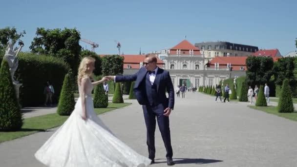 Par promenad nära det stora palatset. Eleganta brudgummen och bruden i bröllop kläder. Kärlek — Stockvideo