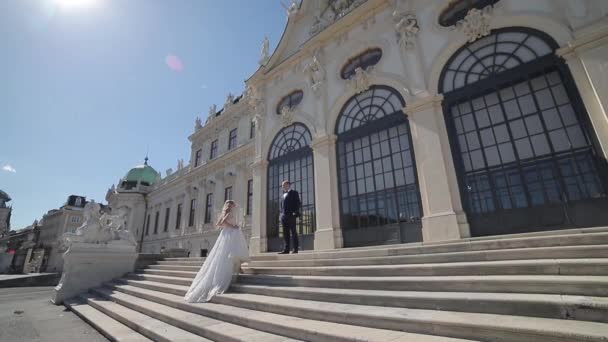 Ženich a nevěsta stojí na schodech velký palác ve Vídni — Stock video