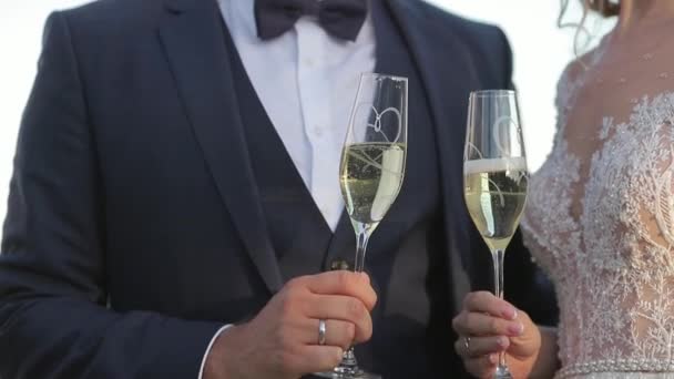 Sposo e sposa stare sullo sfondo della città e bere champagne da bicchiere di vino. Clink bicchieri. Hd video — Video Stock