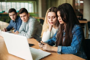 Üniversite öğrencilerinin okul kütüphanesi, bir kız ve bir erkek eğitim grup bir dizüstü bilgisayar kullanarak ve Internet'e bağlanma. Kız