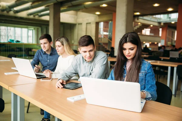 Группа студентов колледжа, обучающихся в школьной библиотеке, девочка и мальчик пользуются ноутбуком и подключаются к интернету — стоковое фото