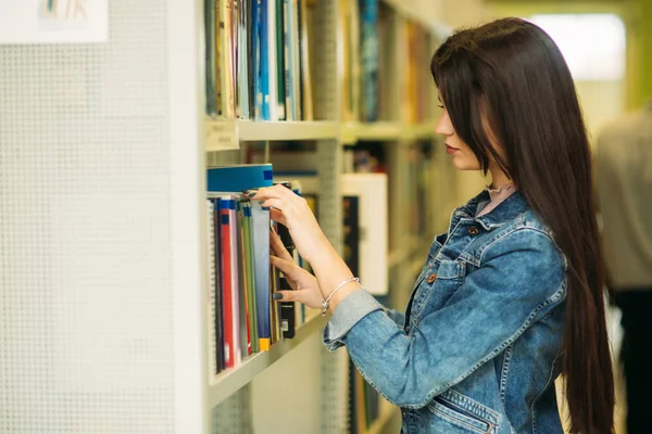 Счастливая юная студентка учится в библиотеке — стоковое фото