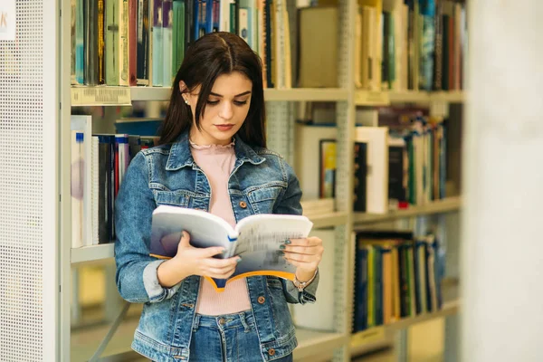 Счастливая юная студентка учится в библиотеке — стоковое фото