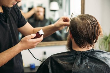 Ana kesim saç ve sakal Berber Dükkanı'nın adamlarından, Kuaför saç modeli için genç bir adam yapar.