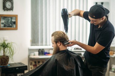 Ana saç ve sakal Berber Dükkanı'nın adamlarından keser ve bir saç kurutma makinesi kullanır