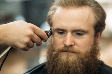 Sakallı adam bir saç kesimi saç kesme makineleri ile sahip