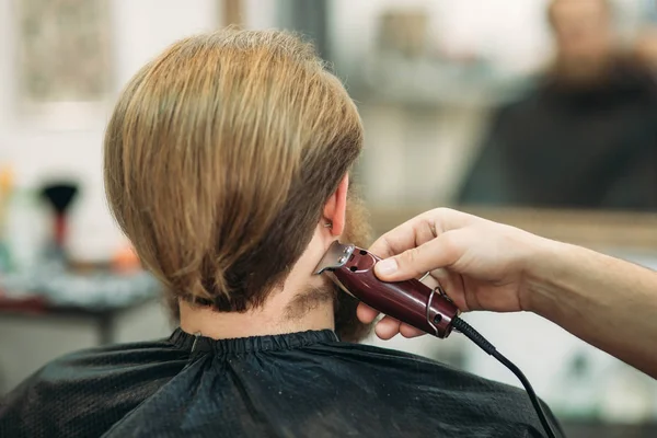 Hombre Barbudo con un corte de pelo con una cortadora de pelo. Vista trasera — Foto de Stock