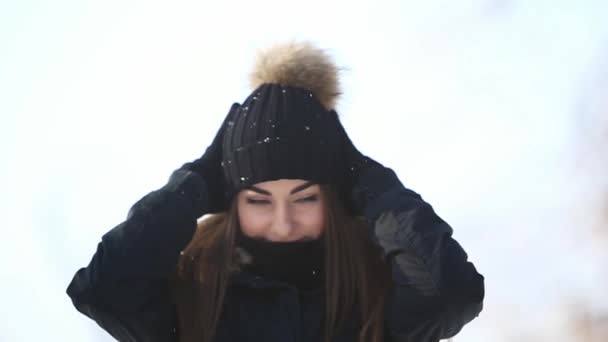 Красива молода жінка взимку. Вона одягнена в темну куртку і капелюх — стокове відео