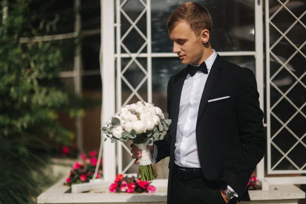 Joven groon en el día de su boda tomar un ramo de flores para su novia —  Fotos de Stock