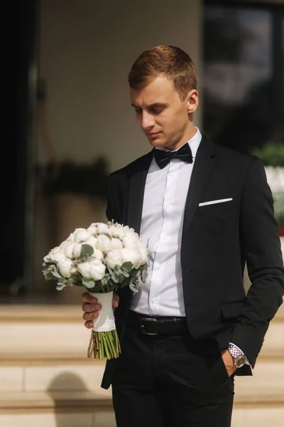 Groon jovem em seu dia do casamento tomar um buquê de flor para sua noiva — Fotografia de Stock