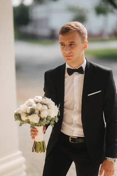 Junger Bräutigam an seinem Hochzeitstag einen Blumenstrauß für seine Braut — Stockfoto