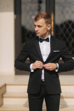 Çekici damat düğün elbise standında otel tarafından. Damat bir papyon giyiyor