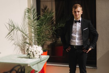 Çekici damat düğün elbise standında otel tarafından. Damat bir papyon giyiyor