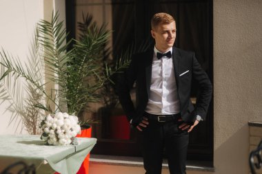 Çekici damat düğün elbise standında otel tarafından. Damat bir papyon giyiyor