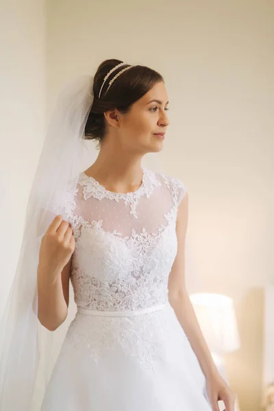 Bela noiva ficar perto da janela em vestido de noiva branco. Senhora encantadora — Fotografia de Stock