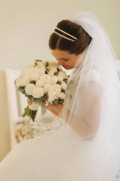 Giovane e tenerezza sposa in abito da sposa tenere bouquet. Felice sposa nel giorno del suo matrimonio — Foto Stock