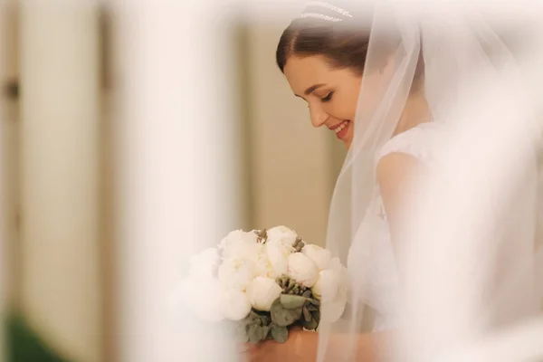 Giovane e tenerezza sposa in abito da sposa tenere bouquet. Felice sposa nel giorno del suo matrimonio — Foto Stock