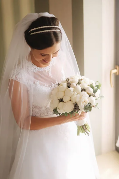 Jeune mariée tendre en robe de mariée tenir bouquet. Mariée heureuse dans son jour de mariage — Photo