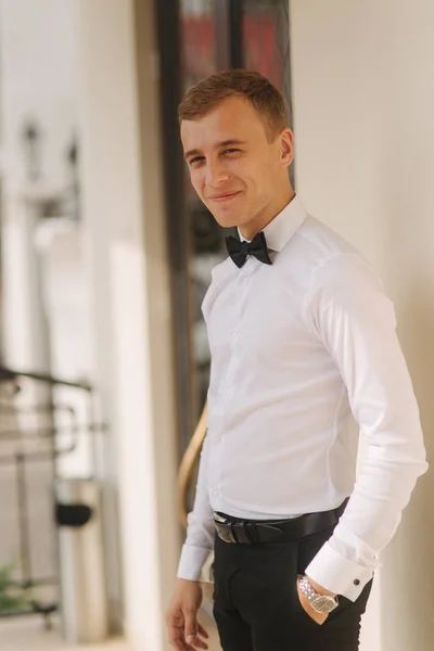 Handsome blonde hair man in shirt and bow tie stand by the hotel — Stock Photo, Image