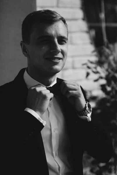 Attractive groom in wedding suit stand by the hotel. The groom wears a bow tie — Stock Photo, Image