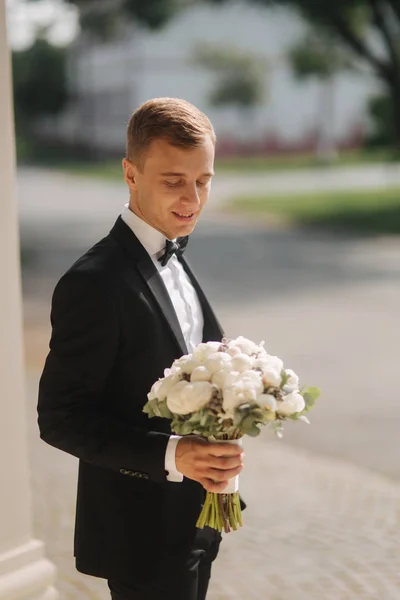 Glad brudgummen i snygg kostym ta brudar bukett och leende — Stockfoto