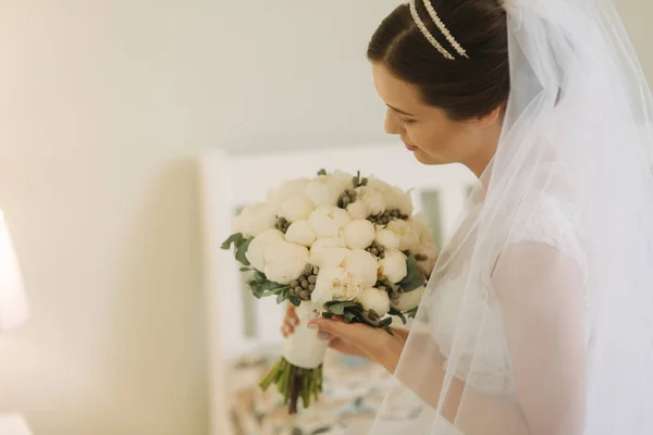 Bella e tenerezza sposa in abito bianco e velo. Tenga il mazzo di fiori in mani — Foto Stock