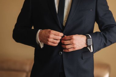 Yakışıklı damat takım elbise standında pencerenin yanında. Giydiği bir kravat ve izle