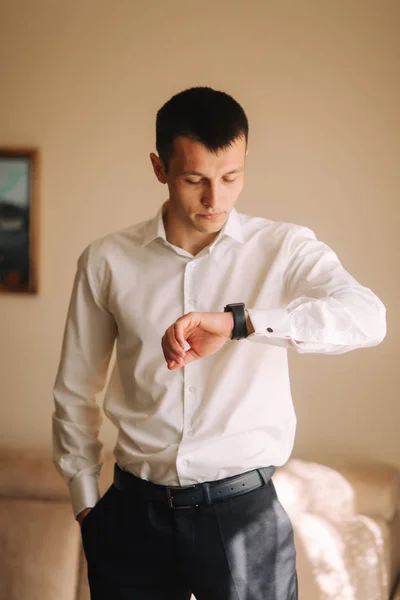 Schöner Bräutigam an seinem Hochzeitstag. Mann beim morgendlichen Anziehen. Blick auf die Uhr — Stockfoto