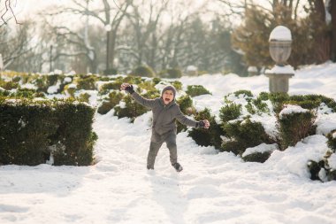 Kış giysileri içinde bir oğlan kar atlar