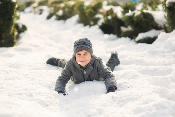 Um menino de roupas de inverno salta para a neve — Fotografia de Stock