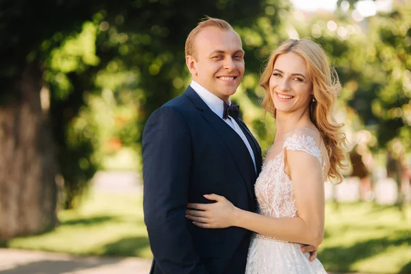 Jovem casal feliz em seu dia do casamento passar o tempo no parque. Fundo verde — Fotografia de Stock