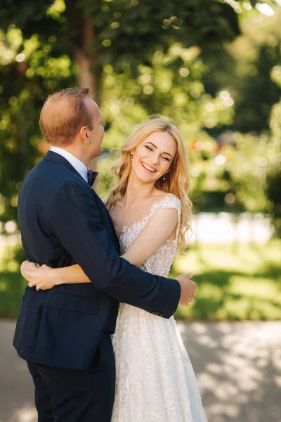 Glückliches junges Paar in ihrem Hochzeitstag verbringen Zeit im Park. grüner Hintergrund — Stockfoto