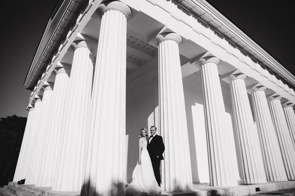 Мужчина и женщина в свадебной одежде стоят рядом с большой колонной — стоковое фото