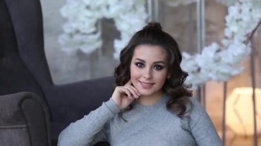 Koltuk yakınındaki hamile kadın sit. Yatak ışıkları ile arka plan. Güzel kadın evde vakit geçirmek