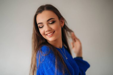 Güzel esmer kız mavi bir bluz bir fotoğrafçısına poz ve ona makyaj gösteren güzel bir gülümseme