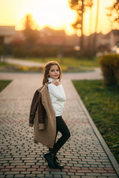 Little girl walk in the park in golden autumn. She hold coat and poses to photographer — Stock Photo, Image