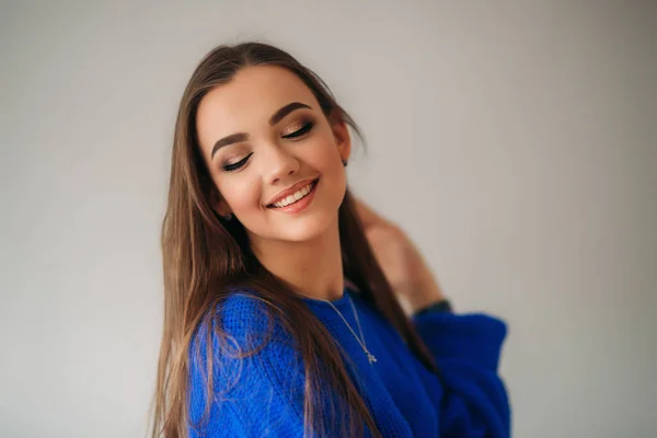 Bella ragazza bruna con un bel sorriso in una camicia blu in posa per un fotografo e mostrando il suo trucco — Foto Stock