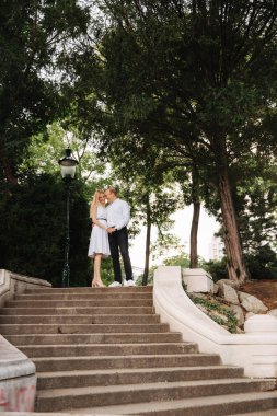 Güzel cuple merdivenlerde dur ve birbirlerine sarılmak. Erkek ve kadın parkta yürüyüş. LoveStory