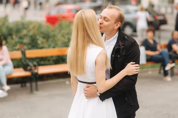 Hombre guapo besa a su encantadora esposa. Hermosa mujer en vestido blanco abrazar a su marido — Foto de Stock